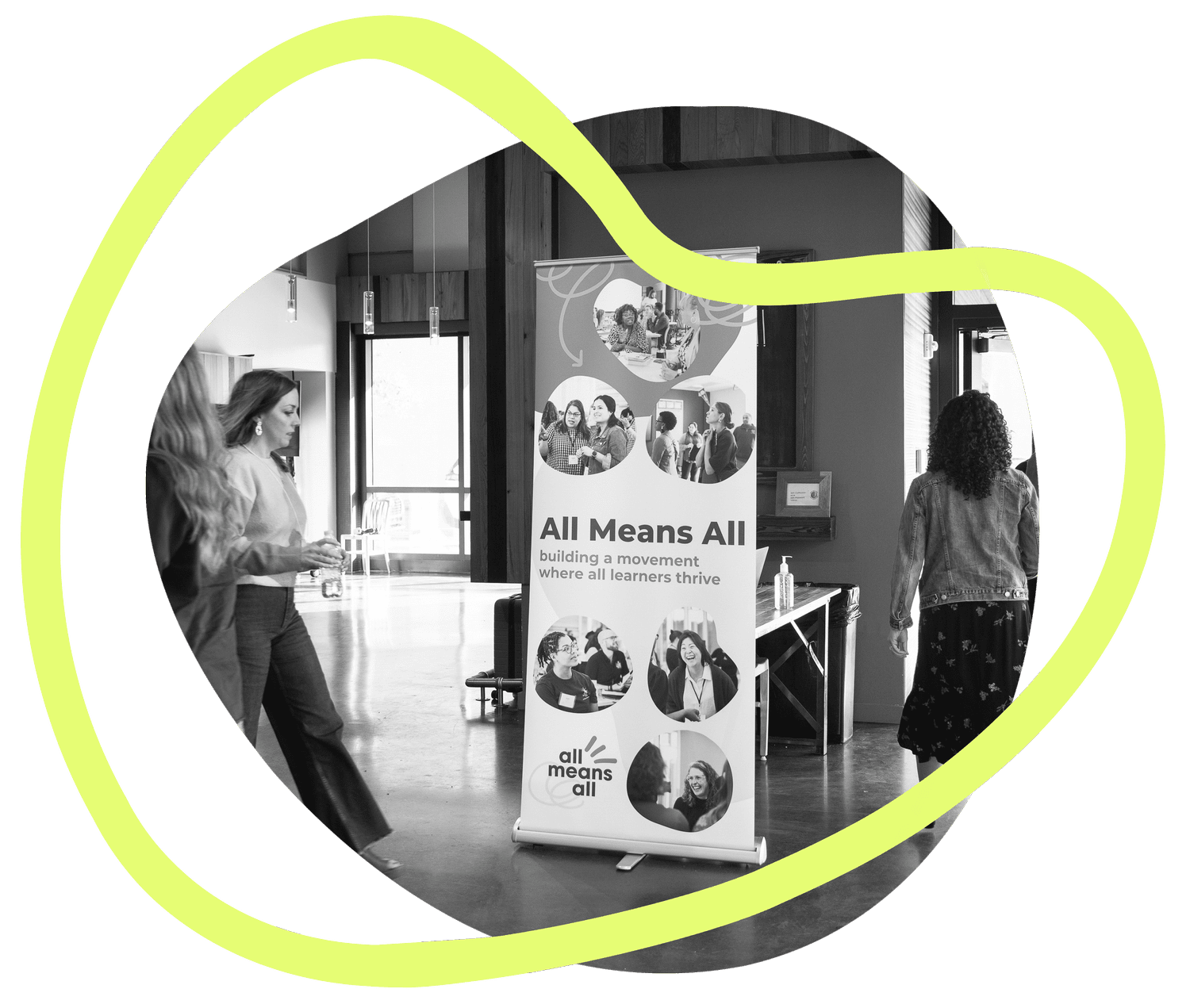 All Means All fellows arriving at a convening, walking past an All Means All banner that reads 'building a movement where all learners thrive.'